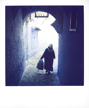 Woman in semi-silhouette walking through archway, Chechaouen, Morocco, North Africa, Africa