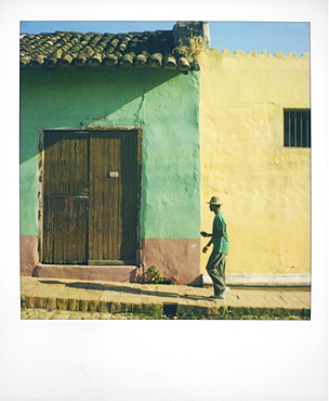 Polaroid of man walking along street against houses painted green and yellow, Trinidad, Cuba, West Indies, Central America