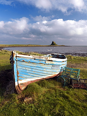 View towards Lindisfarne Castle with old fishing coble and lobster pots in the foreground, Holy Island, Northumberland, England, United Kingdom, Europe