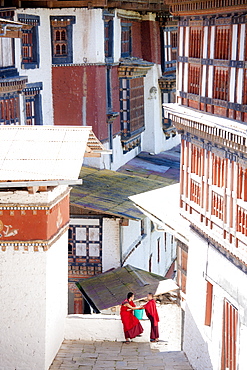 Two Buddhist monks chatting against the imposing backdrop of Trongsa Dzong, Trongsa, Bhutan, Asia