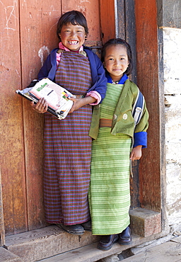 Two young girls, one holding school books, at their school in Ura Village, Ura Valley, Bumthang, Bhutan, Asia