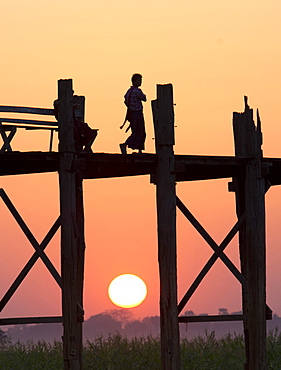 Local man walking on the famous U Bein teak bridge at sunset, near Mandalay, Myanmar (Burma), Asia