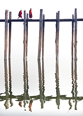 Two Buddhist monks walking across U Bein Bridge, the world's longest teak foot bridge spanning 1300 yards over Taungthaman Lake, Amarapura, near Mandalay, Myanmar (Burma), Asia