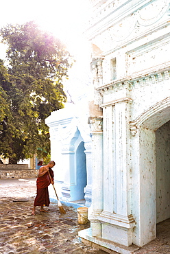 Buddhist monk cleaning paving outside a small temple near the famous U Bein teak bridge, Amarapura, near Mandalay, Myanmar (Burnma), Asia