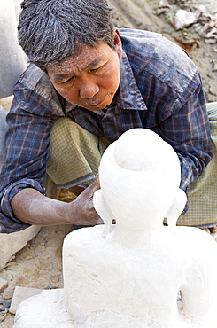 Local man carving a marble Buddha image using an angle grinder, and covered in white marble dust, stone carver's district, Amarapura, near Mandalay, Myanmar (Burma), Southeast Asia