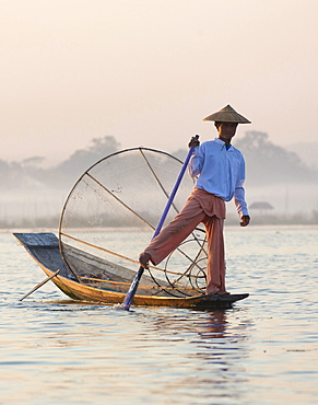 Intha 'leg rowing' fishermen at dawn on Inle Lake who row traditional wooden boats using their leg and fish using nets stretched over conical bamboo frames, Inle Lake, Myanmar (Burma), Southeast Asia