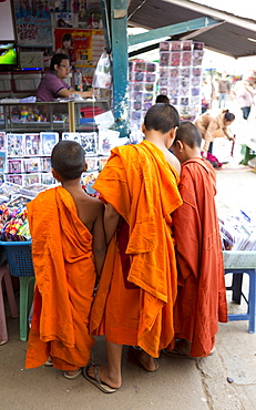 Three novice monks buying comics in the town market, Kengtung (Kyaingtong), Shan State, Myanmar (Burma), Asia