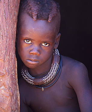 Young Himba boy with plaited hair wearing traditional jewellery around his neck, Kunene Region (formerly Kaokoland) in the far north of Namibia, Africa