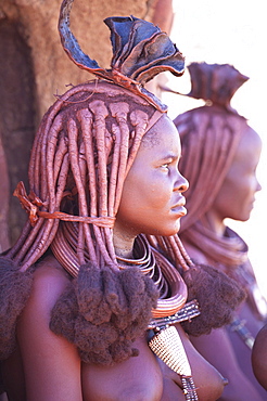 Young Himba woman wearing traditional dress and jewellery and with her skin covered in Otjize, a mixture of butterfat and ochre, Kunene Region, formerly Kaokoland, Namibia