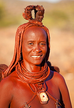 Himba woman wearing traditional leather clothing and jewellery, hair brading and skin covered in Otjize, a mixture of butterfat and ochre, Kunene Region (formerly Kaokoland) in the far north of Namibia, Africa