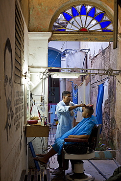 Man having haircut in backstreet barber shop, Havana Viejo, Havana, Cuba, West Indies, Central America 