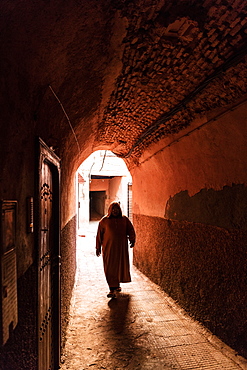 Local man dressed in traditional djellaba walking through archway in a street in the Kasbah, Marrakech, Morocco, North Africa, Africa