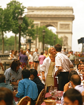 Greeting friends at an outdoor cafe on the Champs Elysees with the Arc de Triomphe behind, Paris, France, Europe