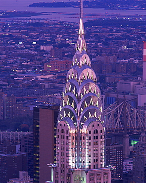 The top of the Chrysler Building illuminated in the evening with a bridge and the city of New York in the background, United States of America, North America