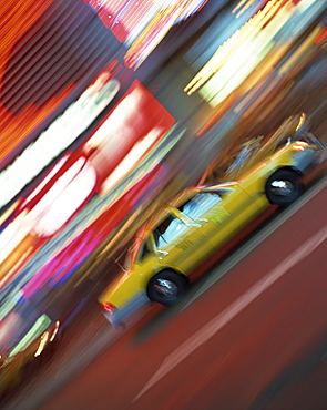 Yellow cab driving past blurred neon lights at night in Times Square in New York, United States of America, North America