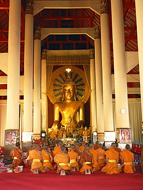 Monks in saffron robes kneel before a statue of the Buddha in Wat Phra Sing in Chiang Mai, Thailand, Southeast Asia, Asia