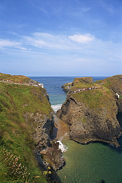 Figures crossing Carrick-A-Rede Bridge over cove, County Antrim, Ulster, Northern Ireland, United Kingdom, Europe