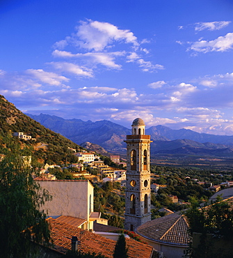 Evening view across rooftops and church tower to mountains, Lumio, near Calvi, Balagne, Corsica, France, Europe