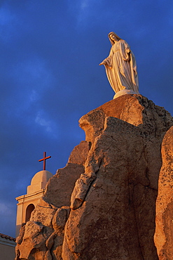 Dawn light on statue of the Virgin and the Chapel of Notre Dame de la Serra, near Calvi, Balagne region, Corsica, France, Europe