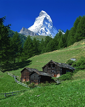 The Matterhorn towering above green pastures, wooden huts in foreground, Zermatt, Valais, Switzerland, Europe