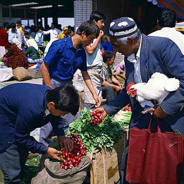 Uzbek man with chicken buying radishes in the central market in the city of Samarkand, Uzbekistan, Central Asia, Asia