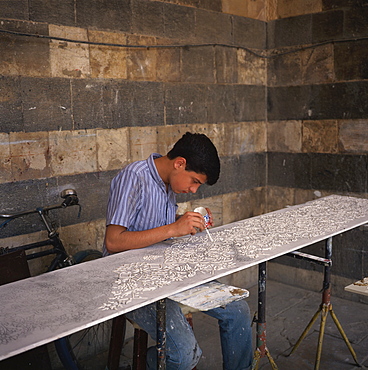 A young craftsman painting detail on a panel, in the craft market at Madrassa Selimiye, Damascus, Syria, Middle East