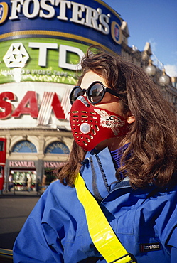 Female cyclist wearing a carbon filtered pollution mask, Piccadilly Circus, London, England, United Kingdom, Europe