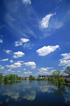 Clouds reflected in a tranquil fishpond in the town of Telc in South Moravia, Czech Republic, Europe