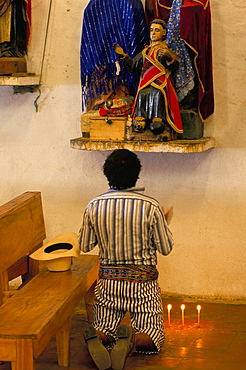 Man in traditional dress praying to Jesus, Santiago Atitlan, Guatemala, Central America