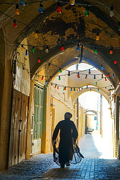 Mullah hurrying down typical vaulted alleyway, Yazd, Iran, Middle East