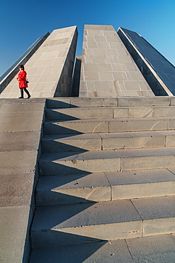 Woman in red walks past Armenian Genocide Memorial building, Yeravan, Armenia, Central Asia, Asia