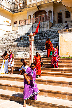 Women in brightly coloured saris walking down the ghats (steps down) barefoot to the sacred water of Pushkar Lake, Pushkar, Rajasthan, India, Asia