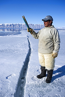 Inuit hunter line fishing at the floe edge for Arctic cod, sculpin and halibut near Herbert Island, Greenland, Denmark, Polar Regions