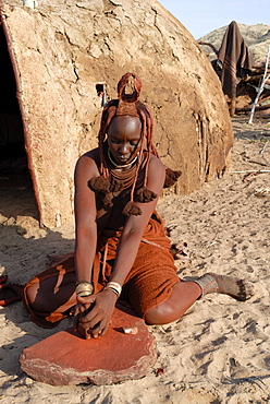 Woman of the Himba tribe grinding pigment for body decoration, Kaokoland, Namibia, Africa