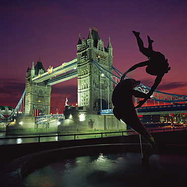 Silhouetted fountain statue and Tower Bridge illuminated at night, London, England, United Kingdom, Europe