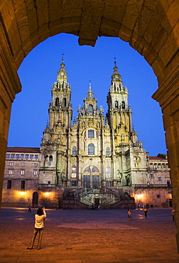 Facade of cathedral seen from Praza do Obradoiro floodlit at night, with a woman taking a photograph, Santiago de Compostela, UNESCO World Heritage Site, Galicia, Spain, Europe