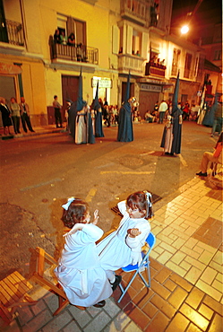 Malaga-Spain - Easter Week (Semana Santa) -Two girls play during a lull in one of the processions 