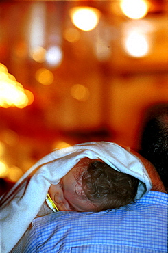 Malaga-Spain - Easter Week (Semana Santa) -A baby sleeps as the lights of a procession pass in background 