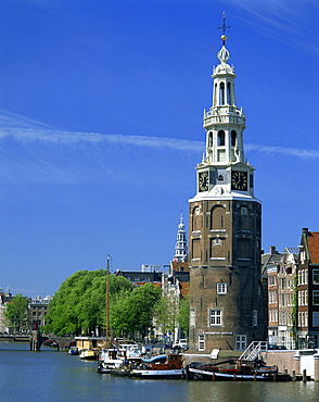 Boats on the canal beside a tower, the Montelbaanstoren, in Amsterdam, Holland, Europe