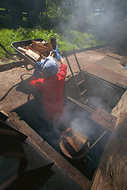 Stoking the smokehouse furnaces for smoking salmon, Scotland, United Kingdom, Europe