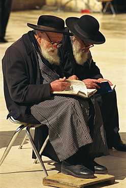 Two old Orthodox Jews sitting praying at the Western or Wailing Wall in the Old City of Jerusalem, Israel, Middle East