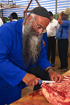 Orthodox Jewish butcher with glasses and long beard, cuts meat at Meron, Israel, Middle East