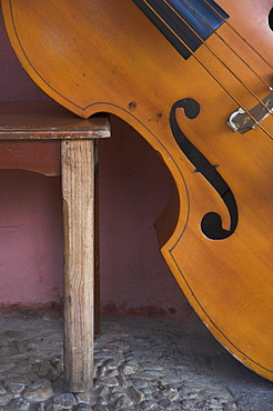 Close-up of a counterbass leaning against a wooden table, Trinidad, Sancti Spiritus province, Cuba, West Indies, Central America