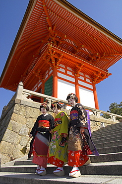 Three geishas in traditional dress walking down steps from main entrance torii, Kiyomizudera temple, UNESCO World Heritage Site, Kyoto, Kansai, Honshu, Japan, Asia