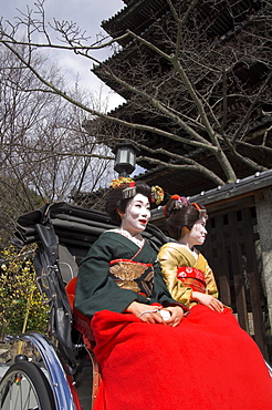 Two geishas in traditional dress posing on a rickshaw, Higashiyama neighbourhood, Kyoto, Kansai, Honshu, Japan, Asia