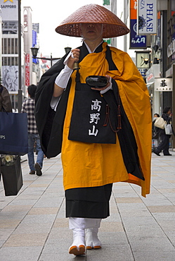 Shinto monk in traditional dress walking on pavement collecting donations, Ginza, Tokyo, Honshu, Japan, Asia