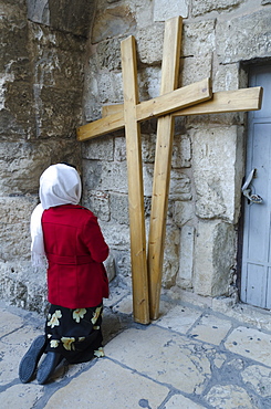 Pilgrim kneeling in front of two wooden crosses at the Holy Sepulchre, Old City, Jerusalem, Israel, Middle East