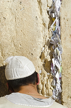 Orthodox Jew praying at Western Wall, with paper notes in crack, Old City, Jerusalem, Israel, Middle East