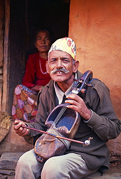 Portrait of a man of Gaines, caste of musicians, playing a stringed instrument and looking at the camera, in Pokhara, Nepal, Asia