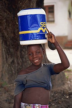 Portrait of a girl carrying water on her head, smiling and looking at the camera, Mozambique, Africa